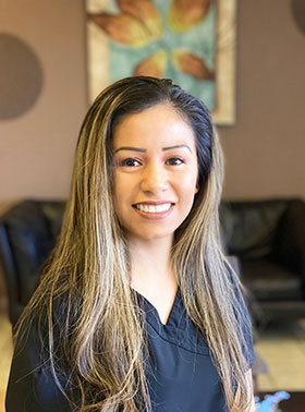 Woman in a white lab coat, smiling and posing for the photo.