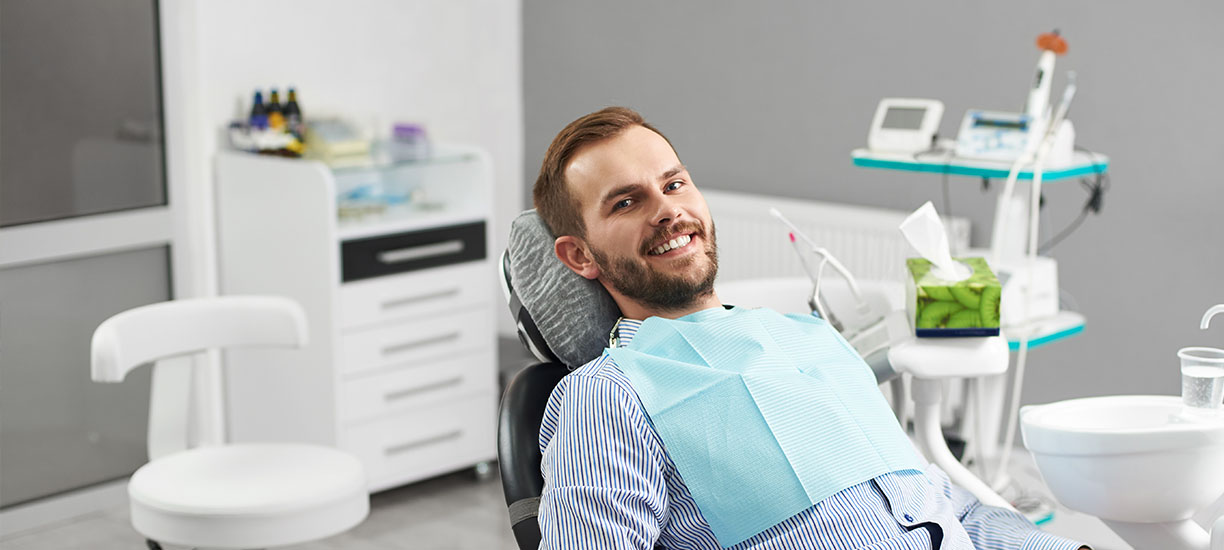 A well-lit reception area with a desk, computer monitor, and potted plant.